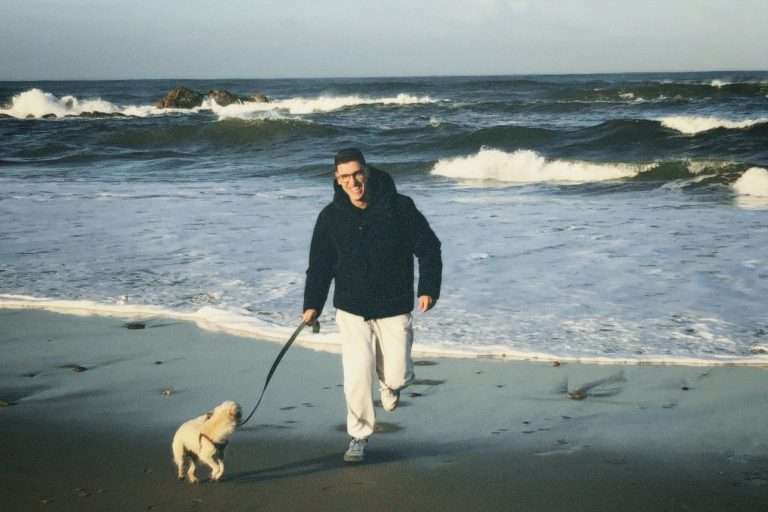 I cani a mare: si possono portare? smiling man walking with a dog on a beach